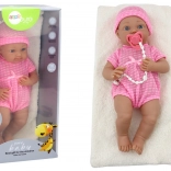 Kisbaba rózsaszín ruhácskában, sapkával, cumival és takaróval